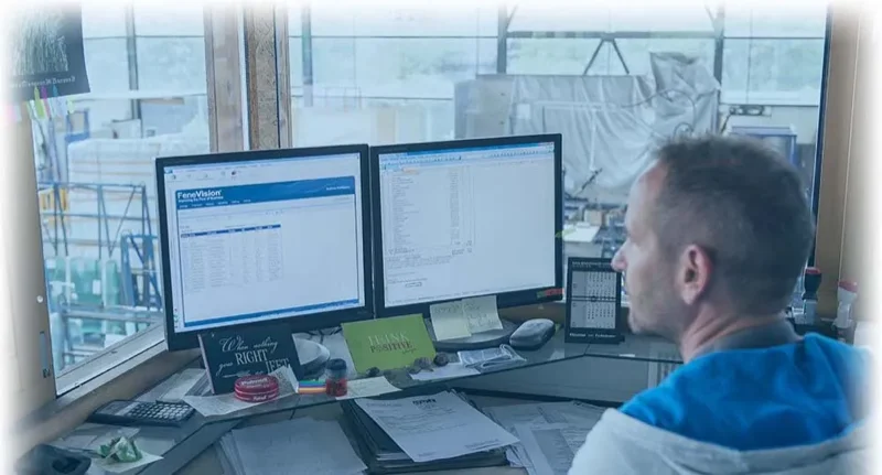 A man at a desk viewing two monitors with software displays